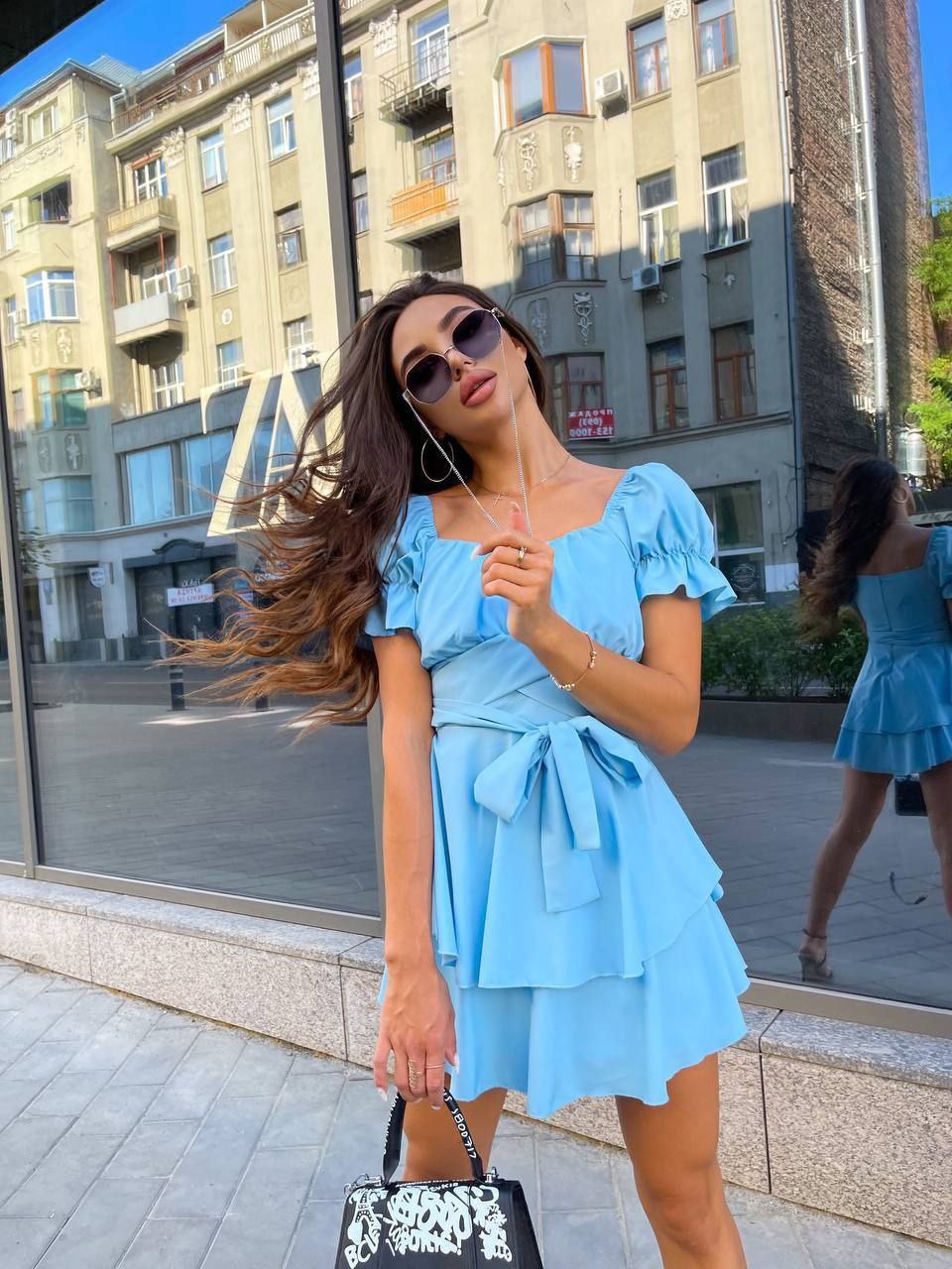 Woman in a blue dress standing on a city street