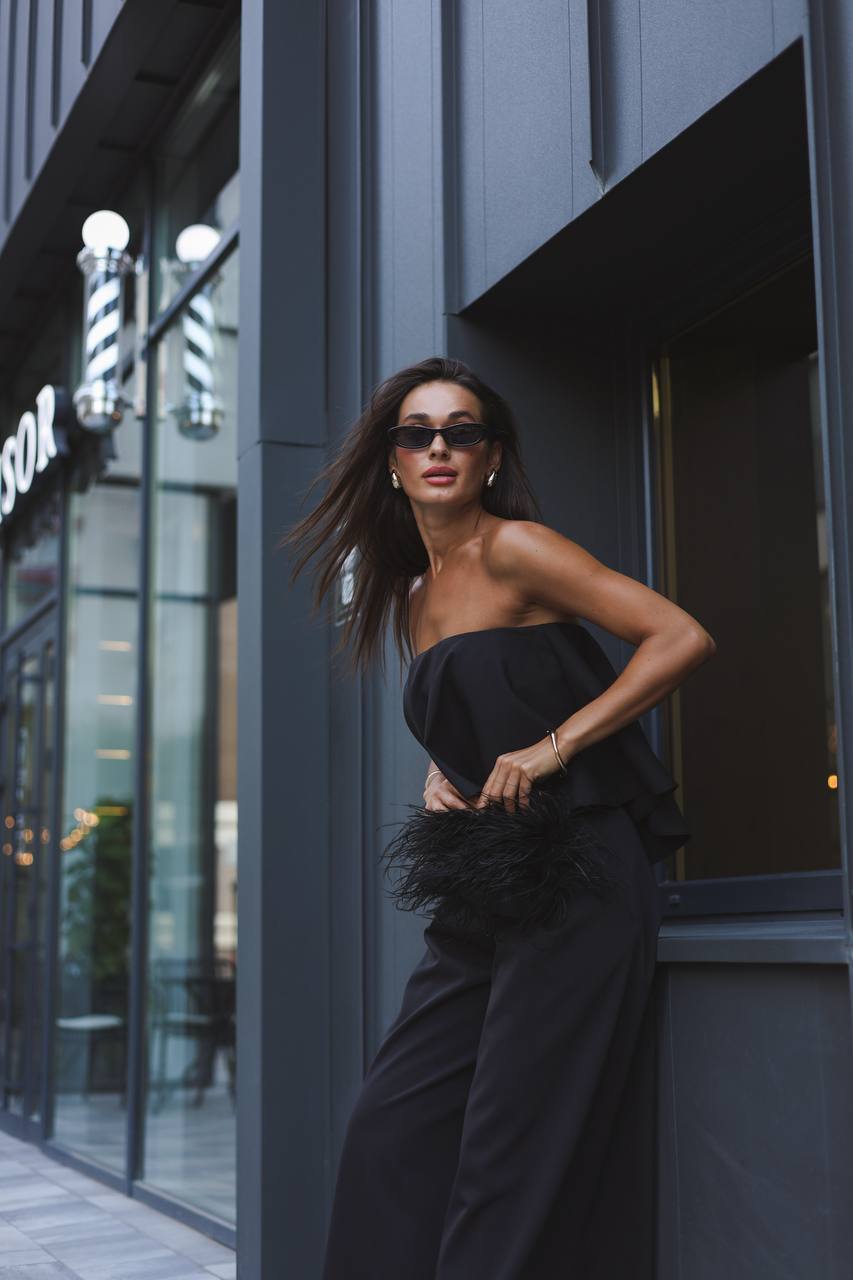 Woman in a black outfit standing against a modern building exterior.