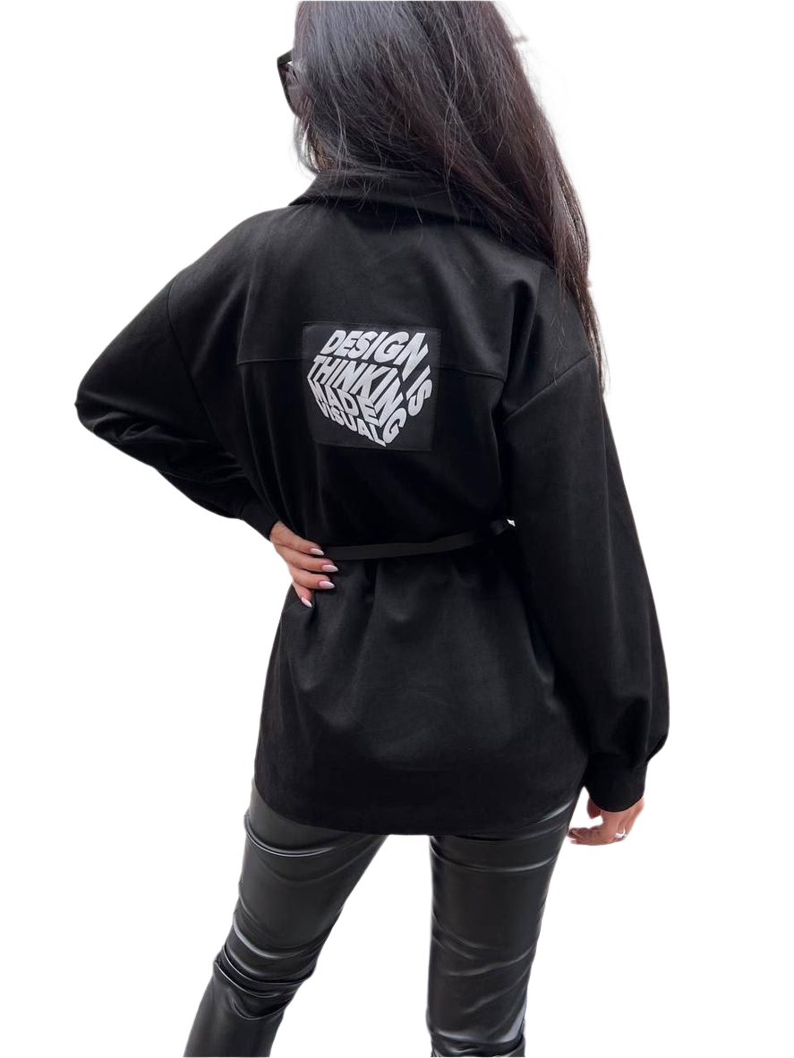 Person wearing a black jacket with text on the back against a white background