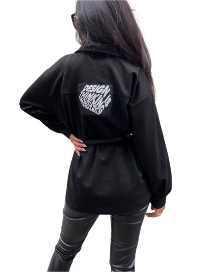 Person wearing a black jacket with text on the back against a white background