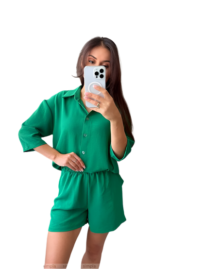 Woman taking a mirror selfie wearing a green outfit on a white background