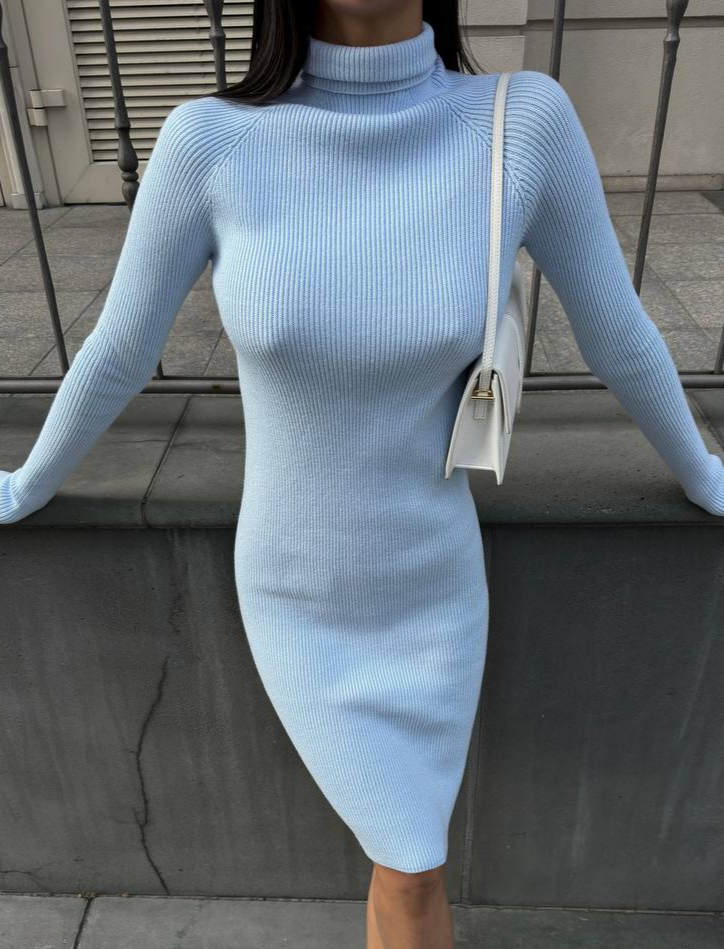 Person wearing a light blue ribbed dress standing against a neutral background