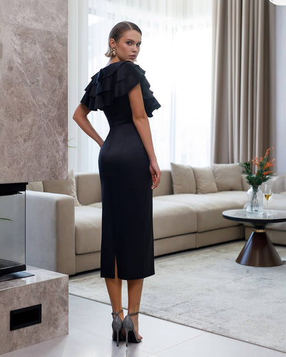 Woman in a black dress standing in a modern living room.