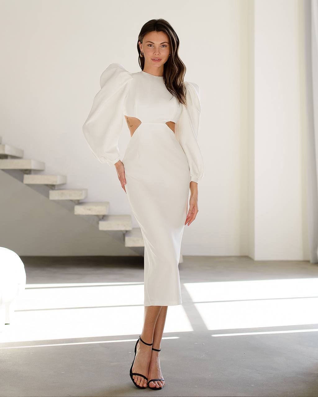 Woman wearing a white dress with cut-out design in a minimalistic setting
