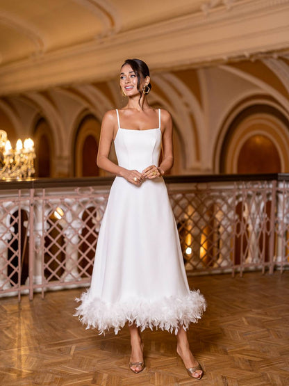 Woman in a white dress standing in an elegant indoor setting with chandeliers.