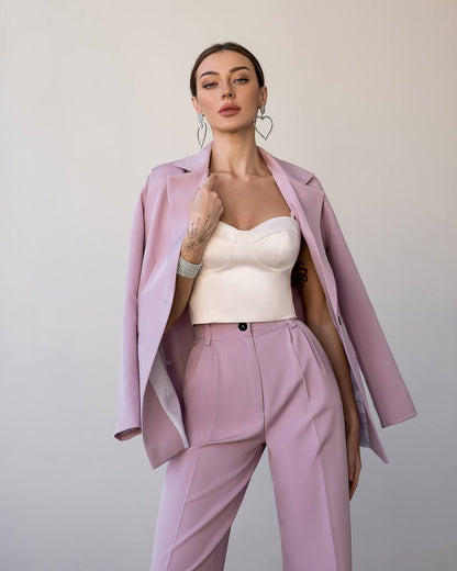 Woman wearing a pink suit with a white top against a plain background