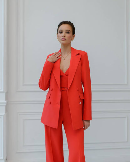 Woman wearing a bright red suit against a white paneled wall