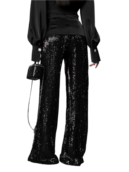 Person wearing black sequin pants with a black top and handbag on a white background