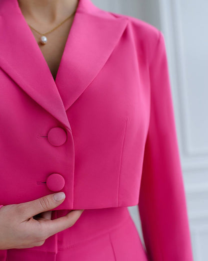 Close-up of a bright pink blazer with buttons, worn by a person.
