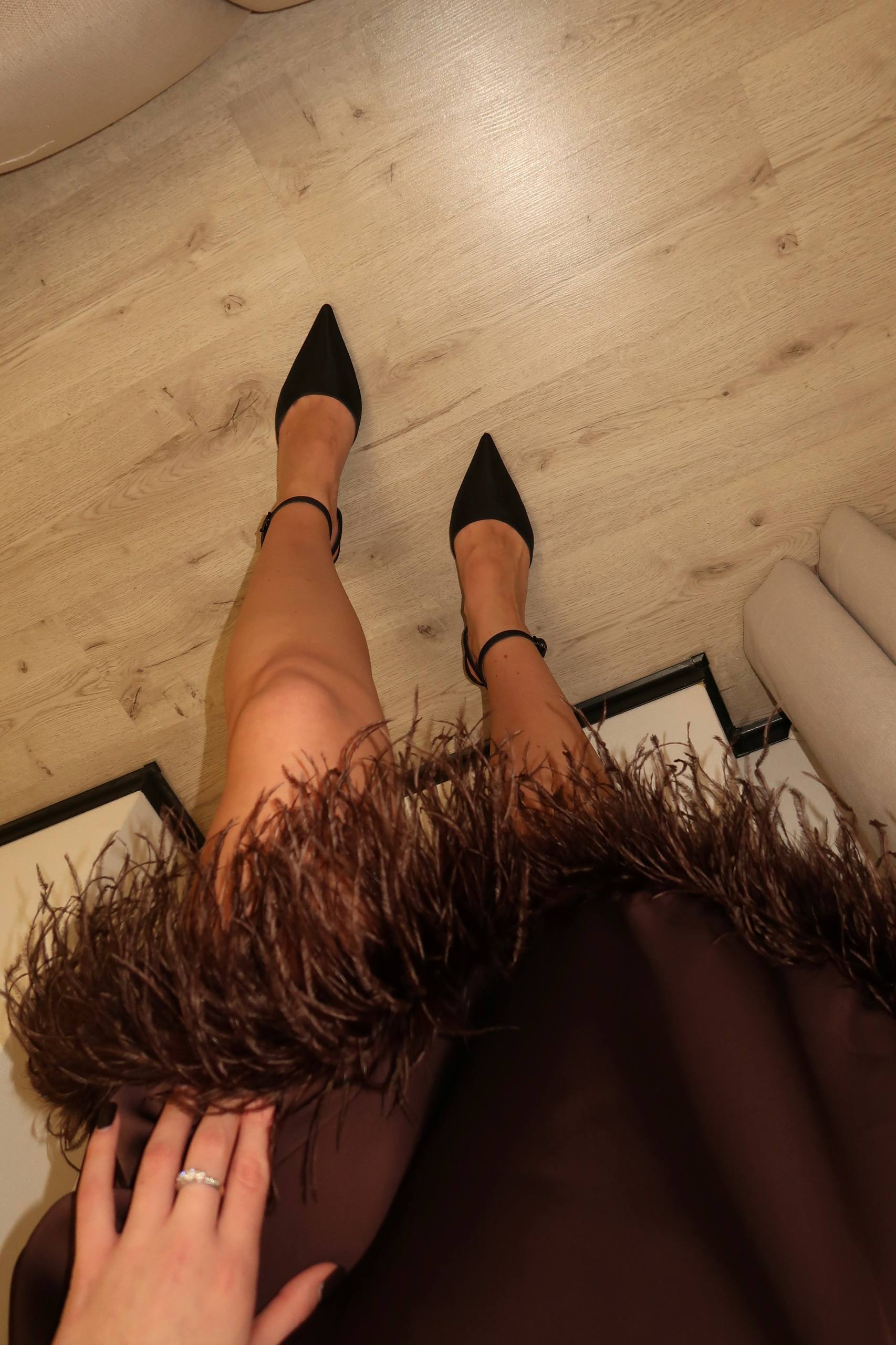 Person wearing black high-heeled shoes on a wooden floor.