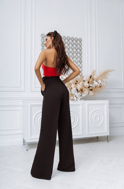 Woman wearing a red top and black high-waisted pants in a stylish room.