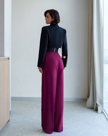 Person wearing a black top and magenta pants in a minimalistic room.