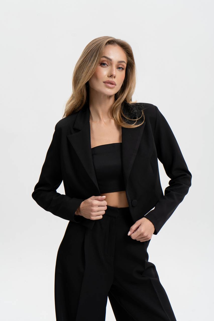 Woman wearing a black blazer and pants on a white background