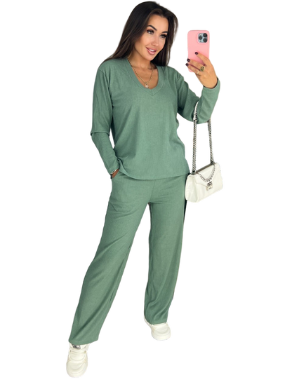 Woman wearing a green outfit taking a selfie on a white background