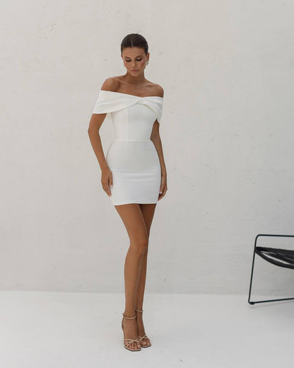 Woman wearing a white off-shoulder dress against a plain background