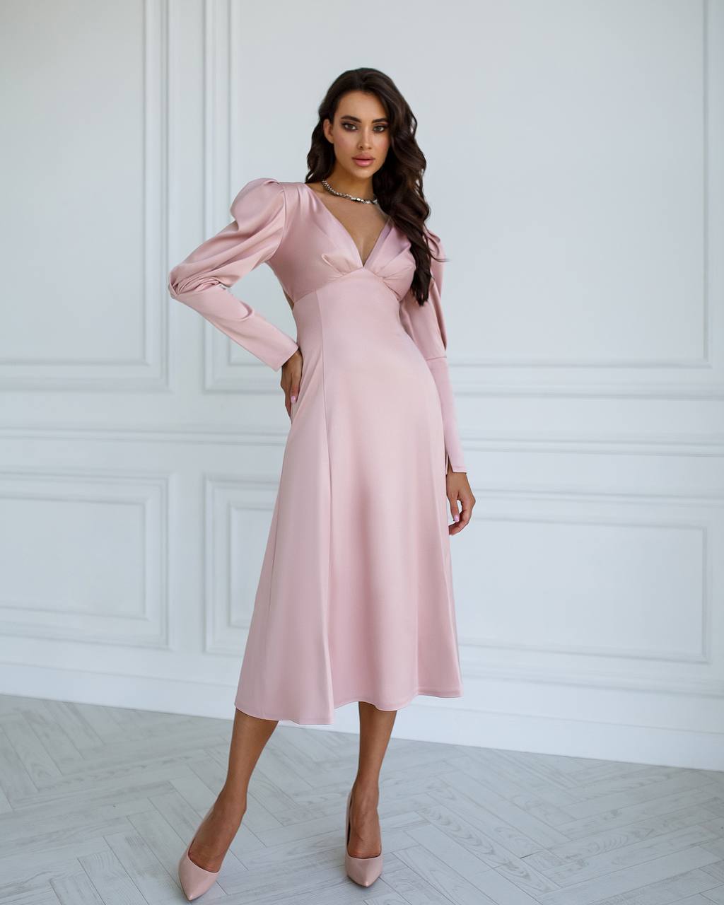 Woman wearing a pink dress against a white wall