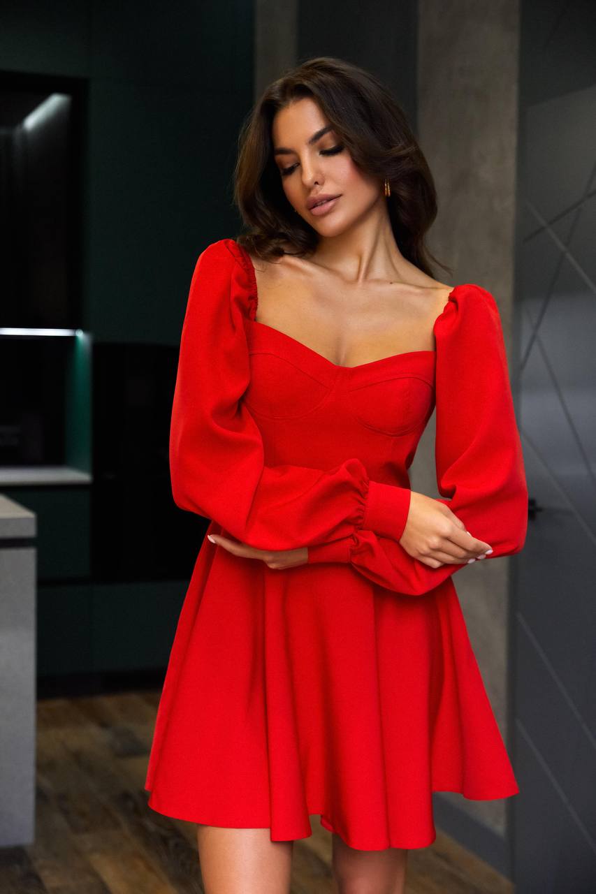 Woman wearing a red dress with long sleeves in an indoor setting
