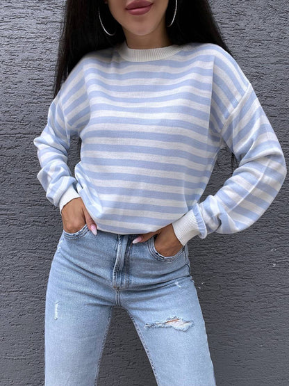 Person wearing a blue and white striped sweater and light blue jeans against a gray background