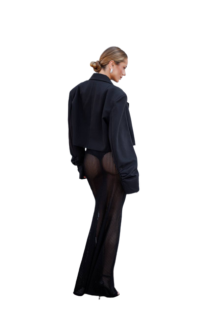Person wearing a black outfit with sheer stockings on a white background