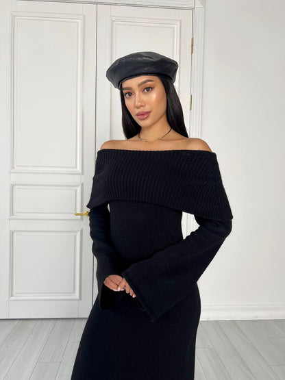 Woman wearing a black off-shoulder dress and cap indoors.