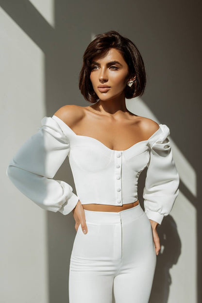 Woman in a white outfit with long gloves against a neutral background
