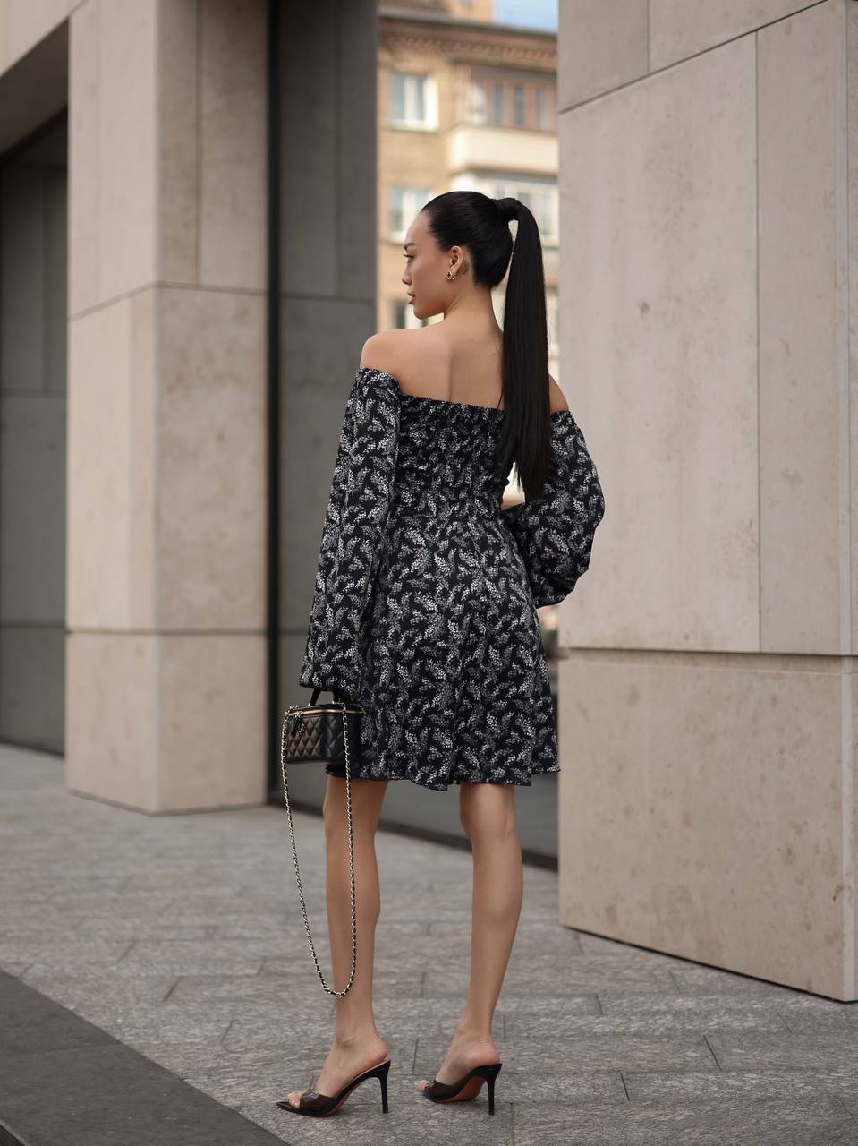Woman in a black and white patterned dress walking outdoors.