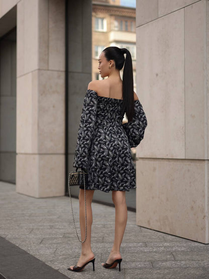 Woman in a black and white patterned dress walking outdoors.