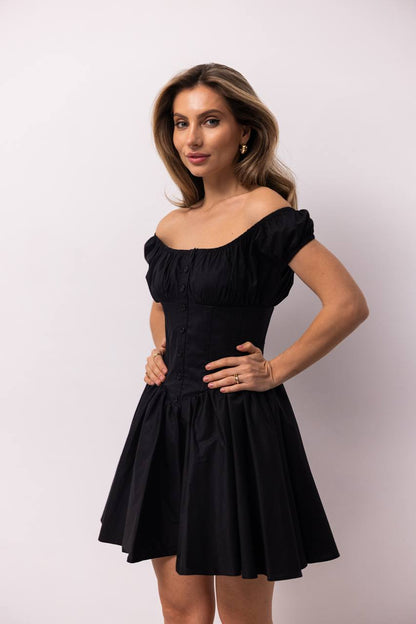 Woman wearing a black off-shoulder dress against a white background