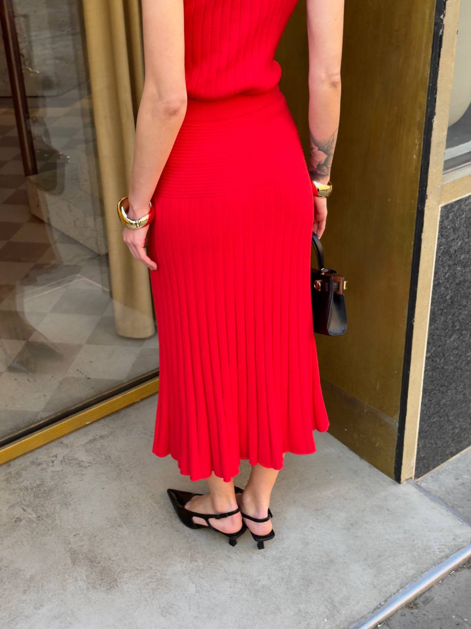 Person wearing a red dress standing in front of a door.