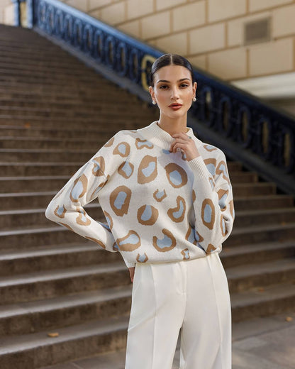 Woman wearing a patterned sweater and white pants standing on steps.
