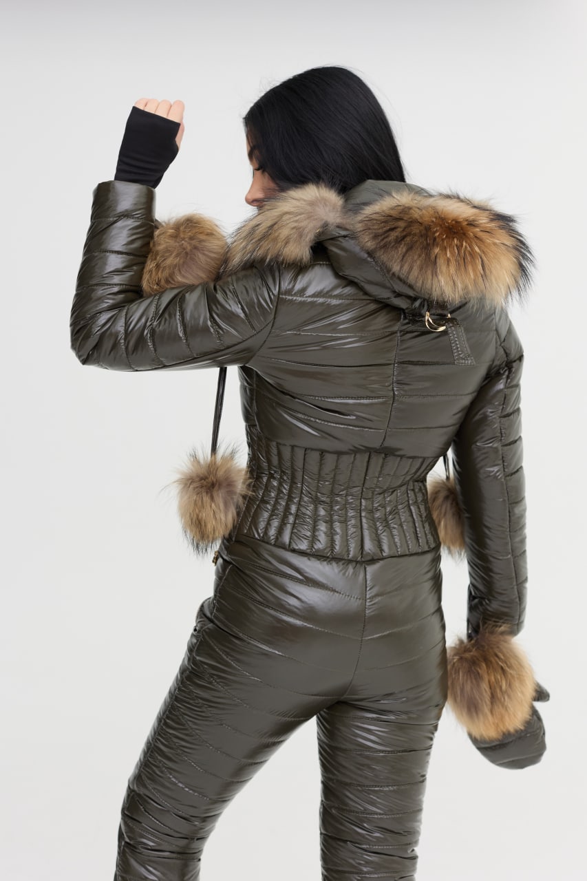 Person wearing a green puffer jacket with fur trim on a white background