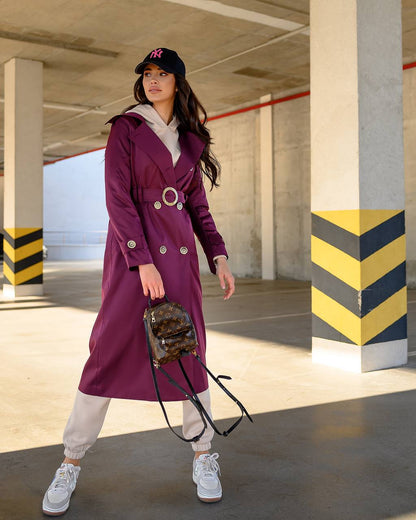 Woman in a purple coat standing in an underground parking garage.