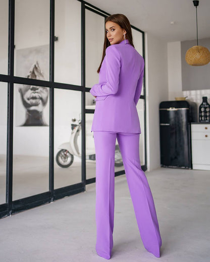 Woman in a purple suit standing in a modern interior setting.