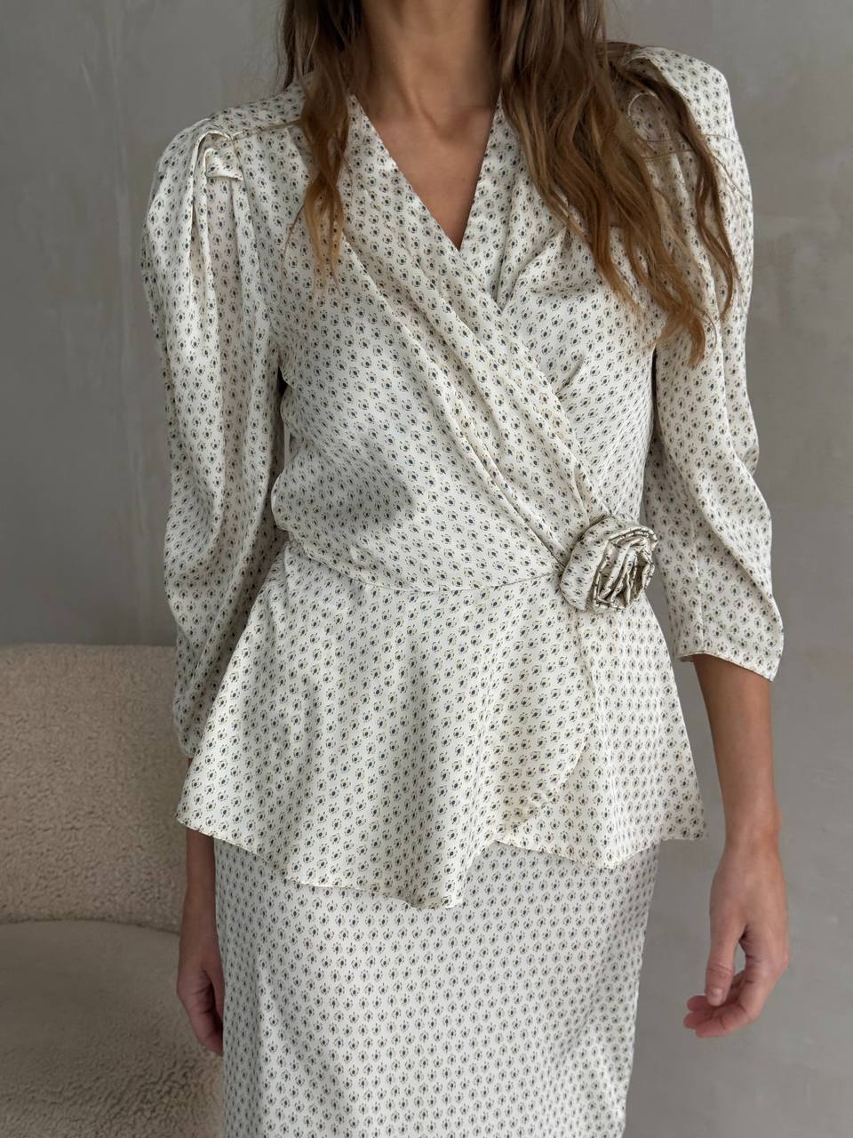 Woman wearing a polka dot blouse and skirt set against a neutral background