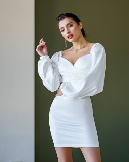 Woman wearing a white dress with puffed sleeves against a neutral background