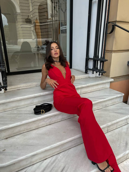Woman in a red jumpsuit sitting on marble steps with a building in the background