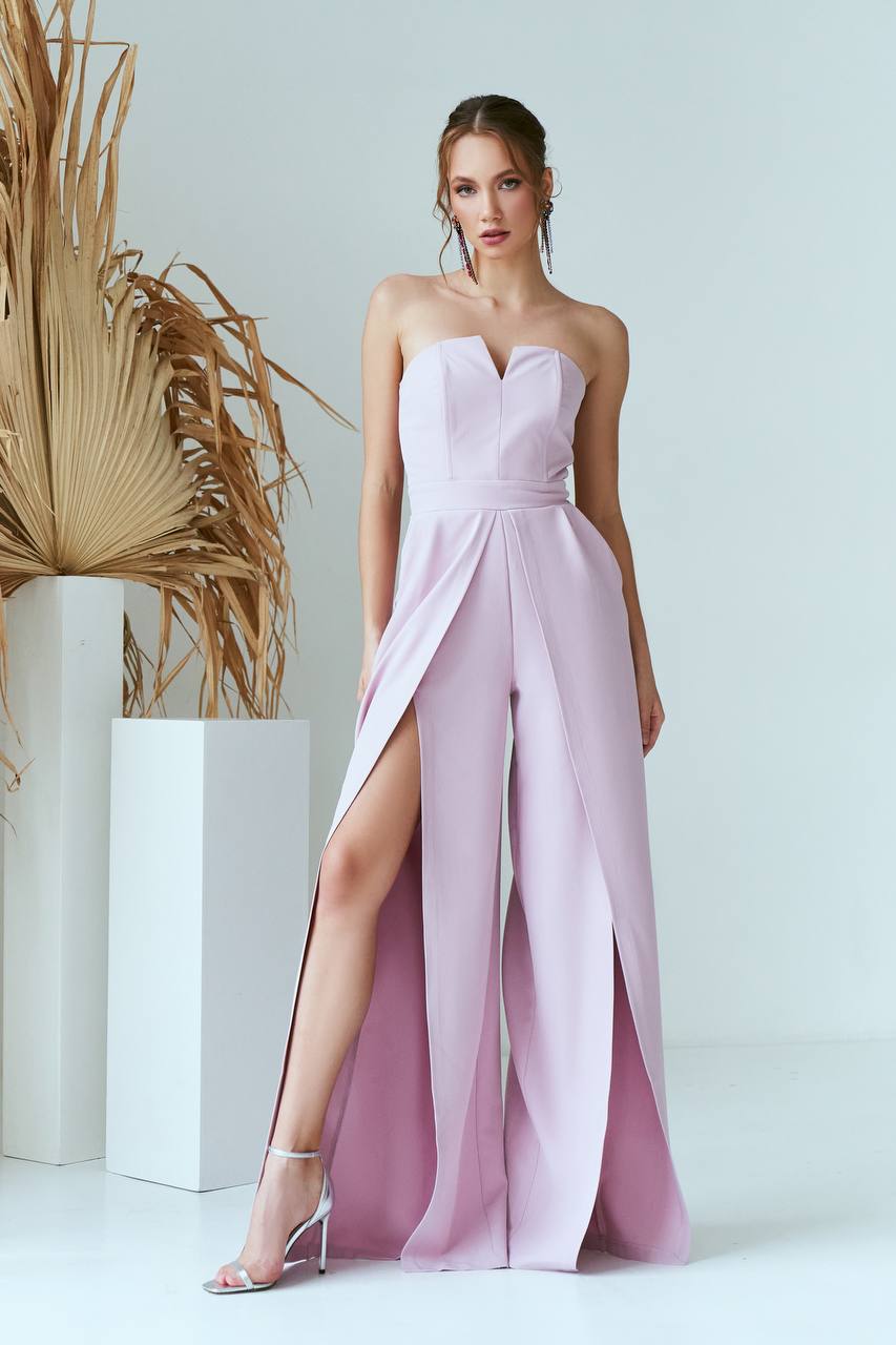 Woman wearing a strapless pink gown with a slit on a white background