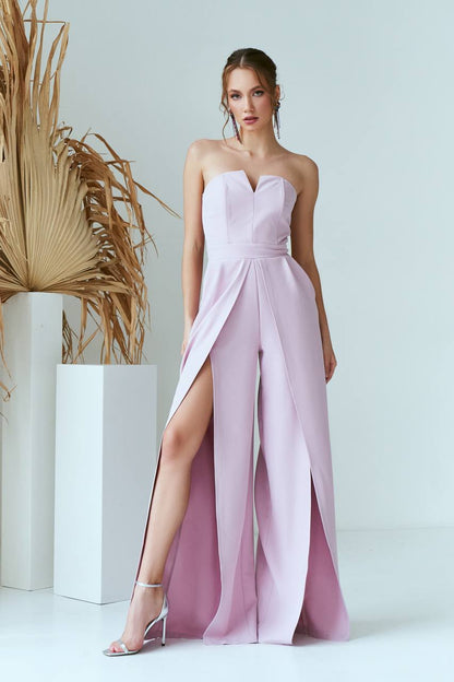 Woman wearing a strapless pink gown with a slit on a white background