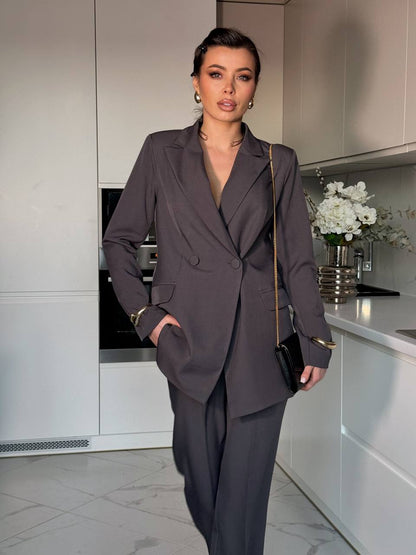 Woman in a gray suit standing in a modern kitchen.