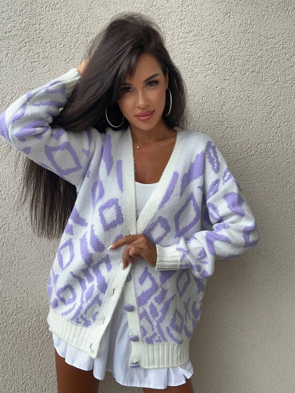 Woman wearing a white cardigan with purple geometric patterns against a plain background