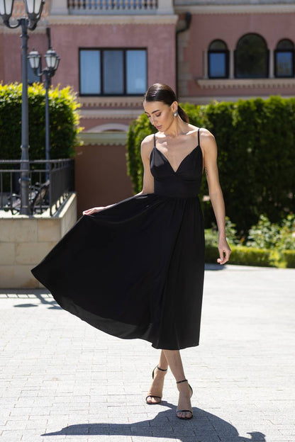 Woman in a black dress standing outdoors with a building in the background
