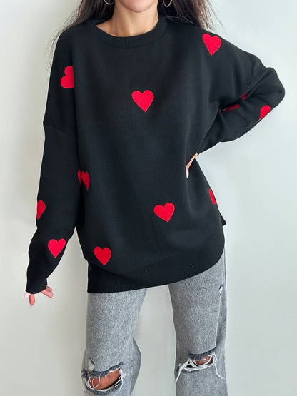 Black sweatshirt with red heart patterns worn by a person against a white background