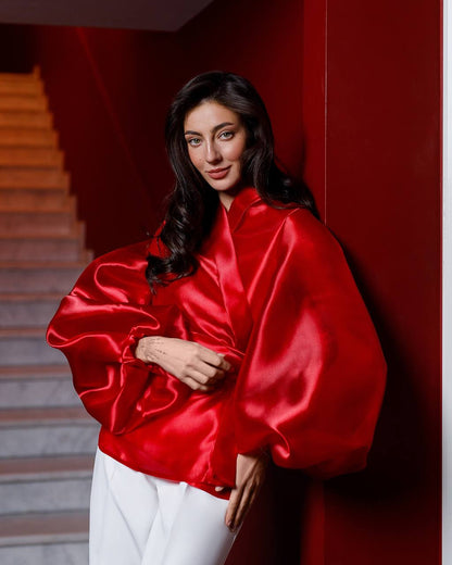 Woman wearing a red satin outfit against a red wall.