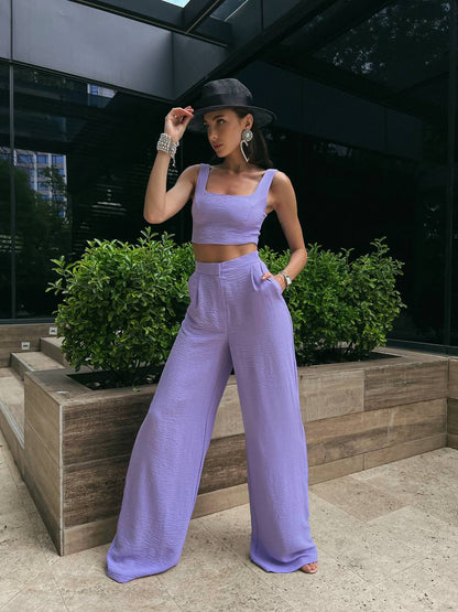 Woman in a lavender outfit posing outdoors with greenery in the background