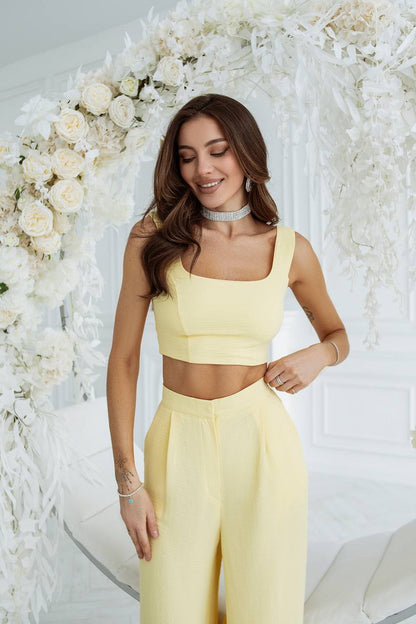 Woman in a yellow outfit standing in front of a white floral arrangement