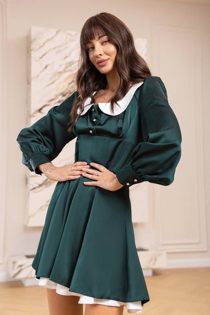 Woman wearing a green dress with a white collar in an indoor setting