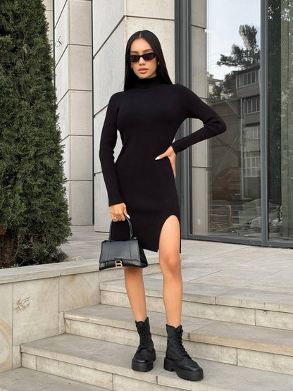 Woman in a black dress with a high slit standing on steps outdoors.