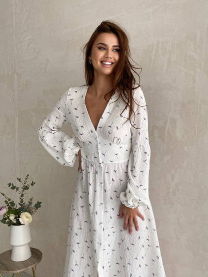 Woman wearing a white dress with a subtle pattern against a plain background