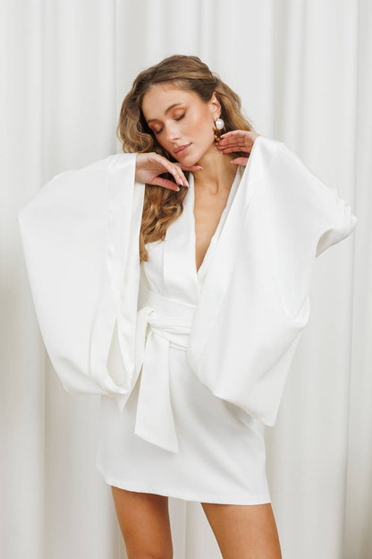 Woman wearing a white dress with a wide collar against a white background