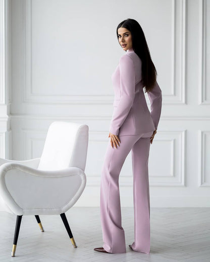 Woman in a pink outfit standing in a room with white walls and a white chair.